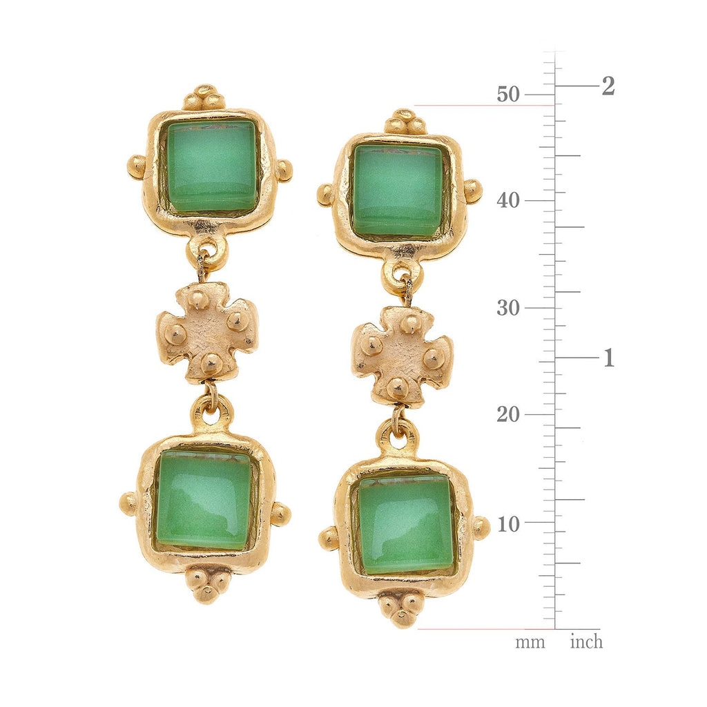 Gold earrings with green gemstones and measurement scale on a white background