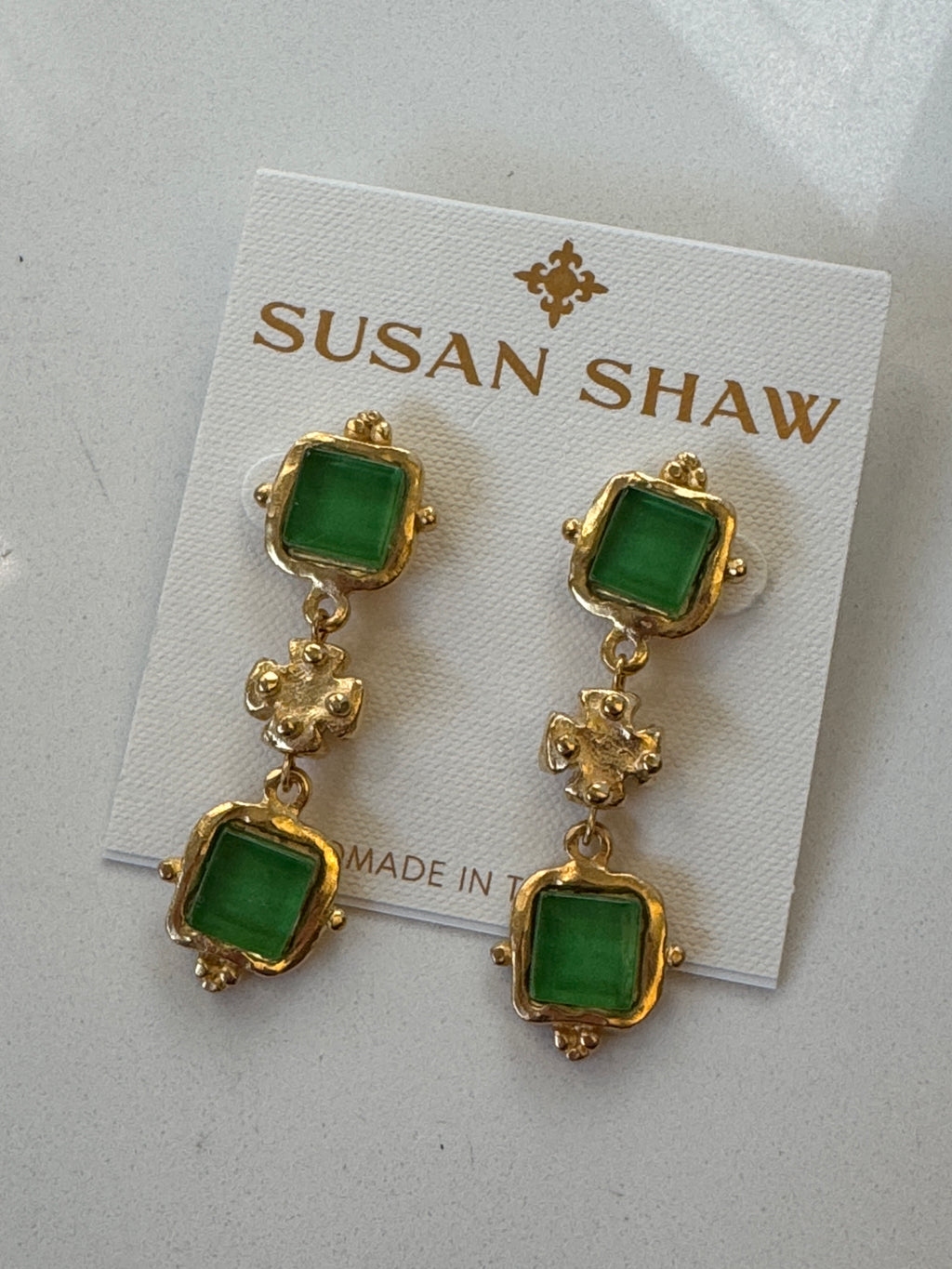 Gold and green earrings on a Susan Shaw branded card.