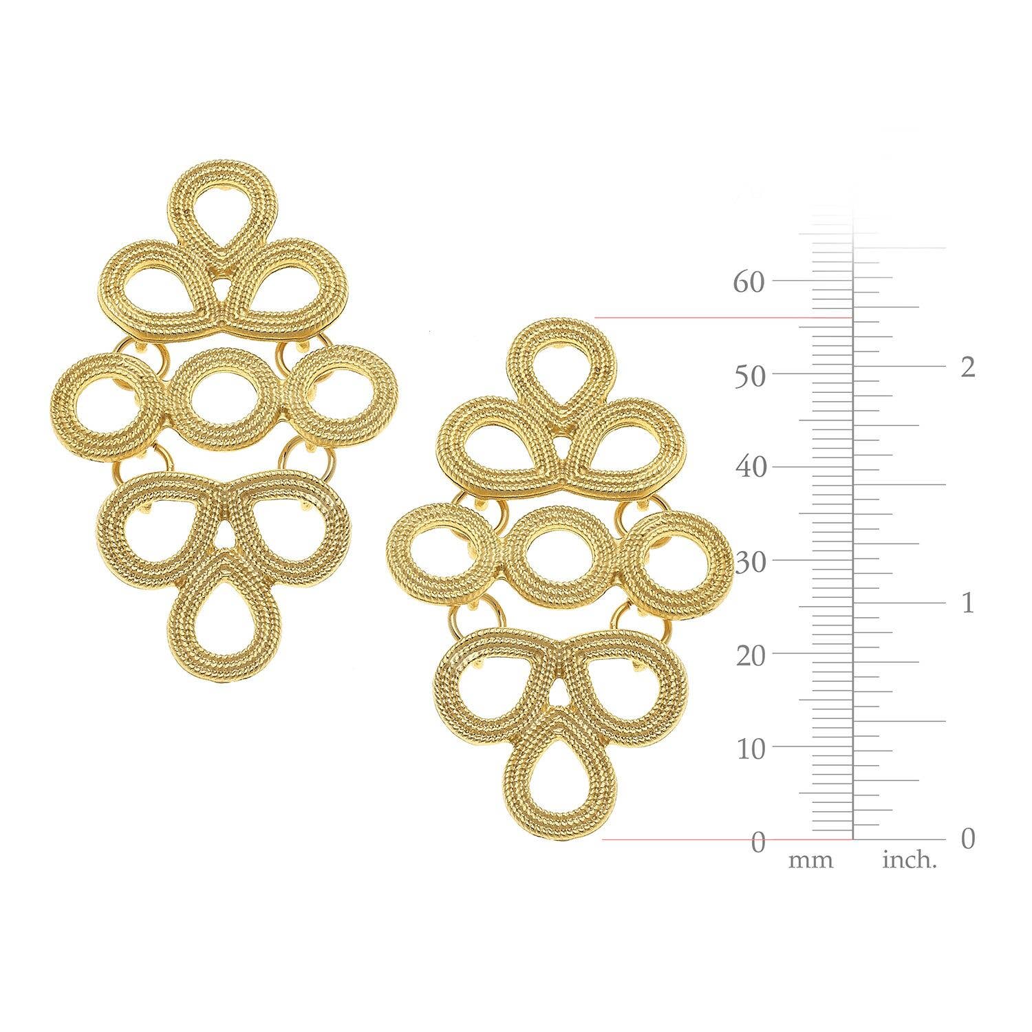 Gold earrings with intricate design and a measurement scale on a white background
