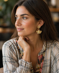 Woman wearing gold earrings with a blurred indoor background