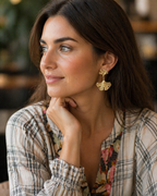Woman wearing gold earrings with a blurred indoor background