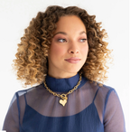 Woman wearing a gold necklace with a heart pendant on a white background