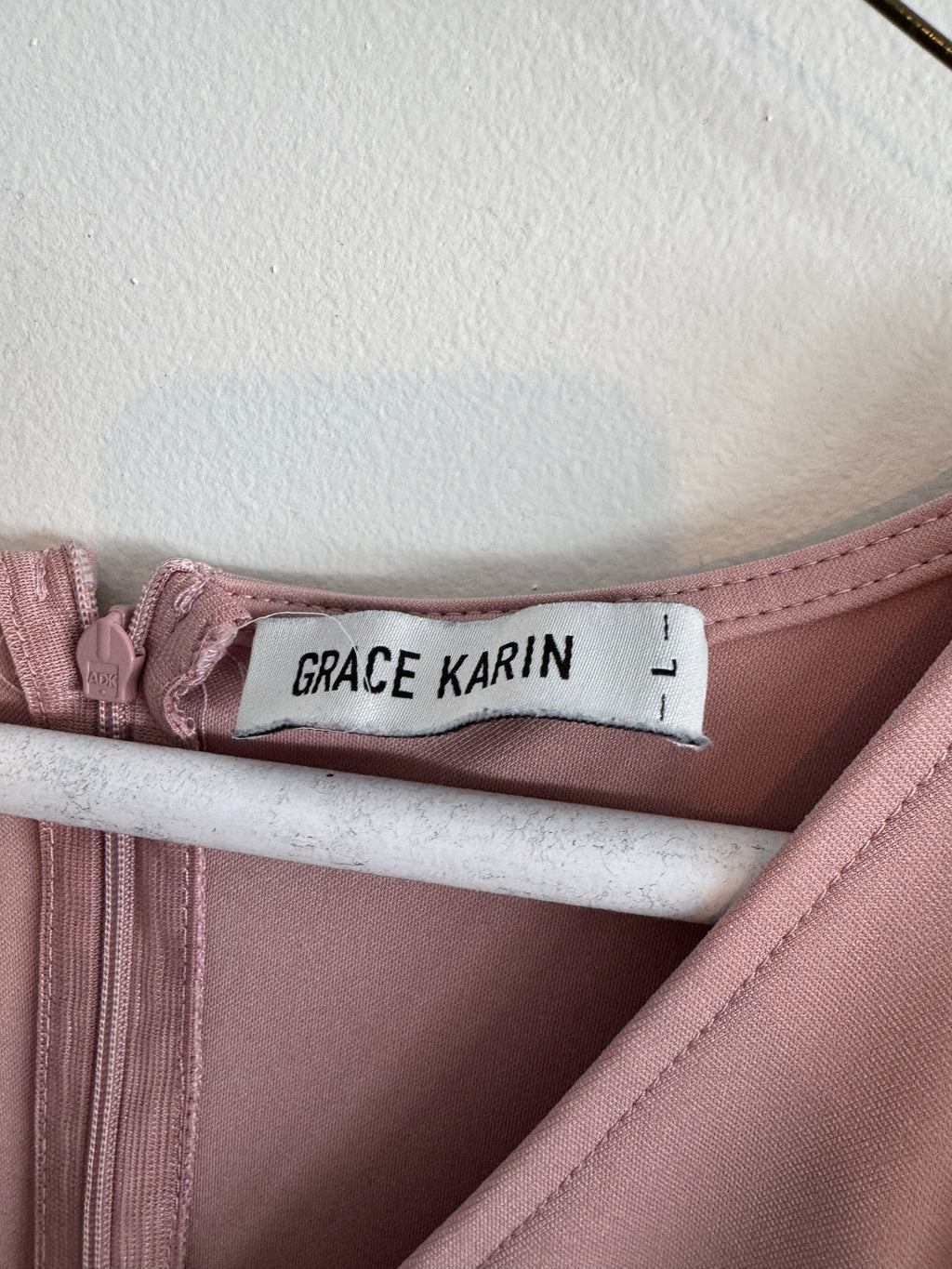Close-up of a garment with a 'Grace Karin' label on a pink fabric background