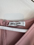 Close-up of a garment with a 'Grace Karin' label on a pink fabric background