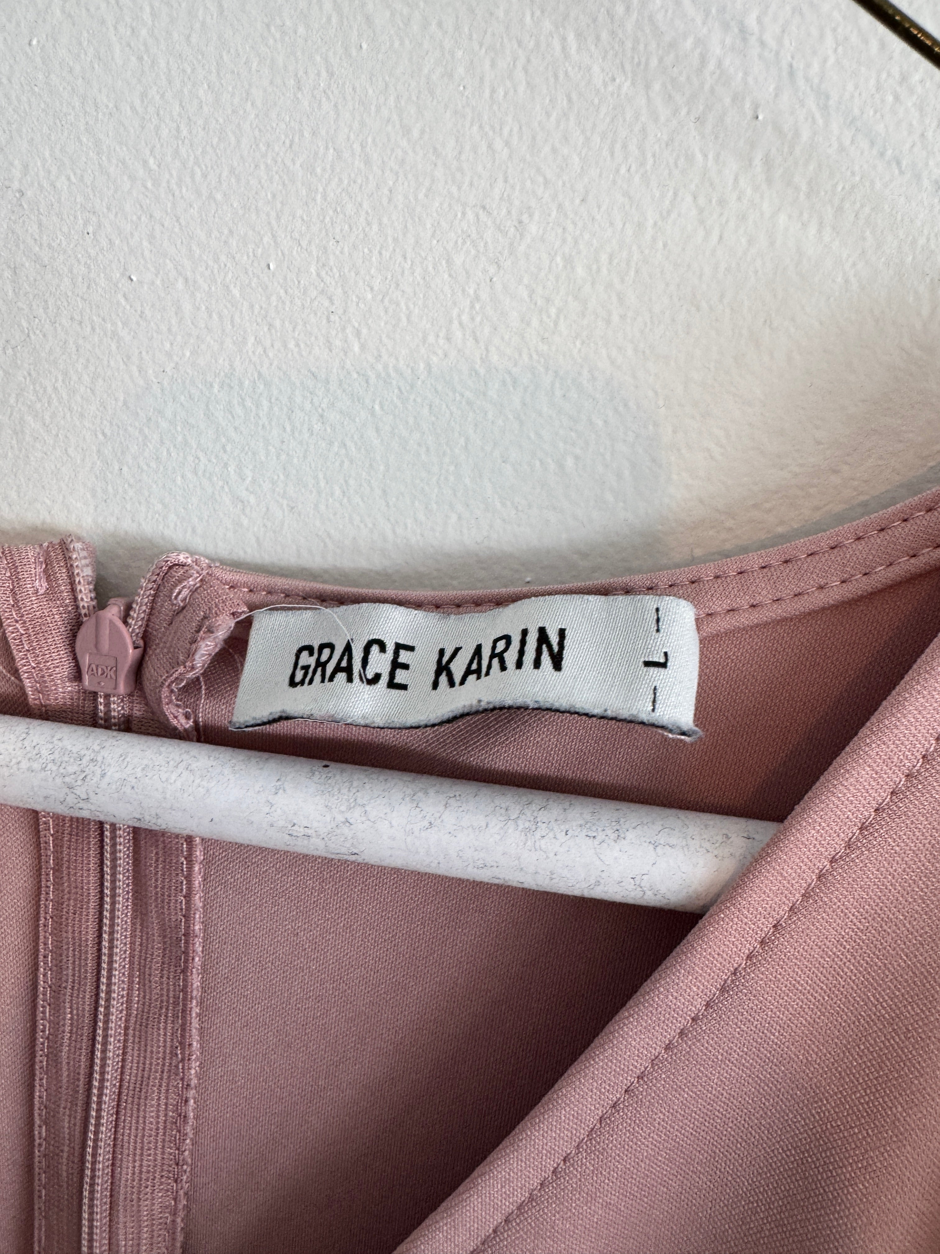 Close-up of a garment with a 'Grace Karin' label on a pink fabric background