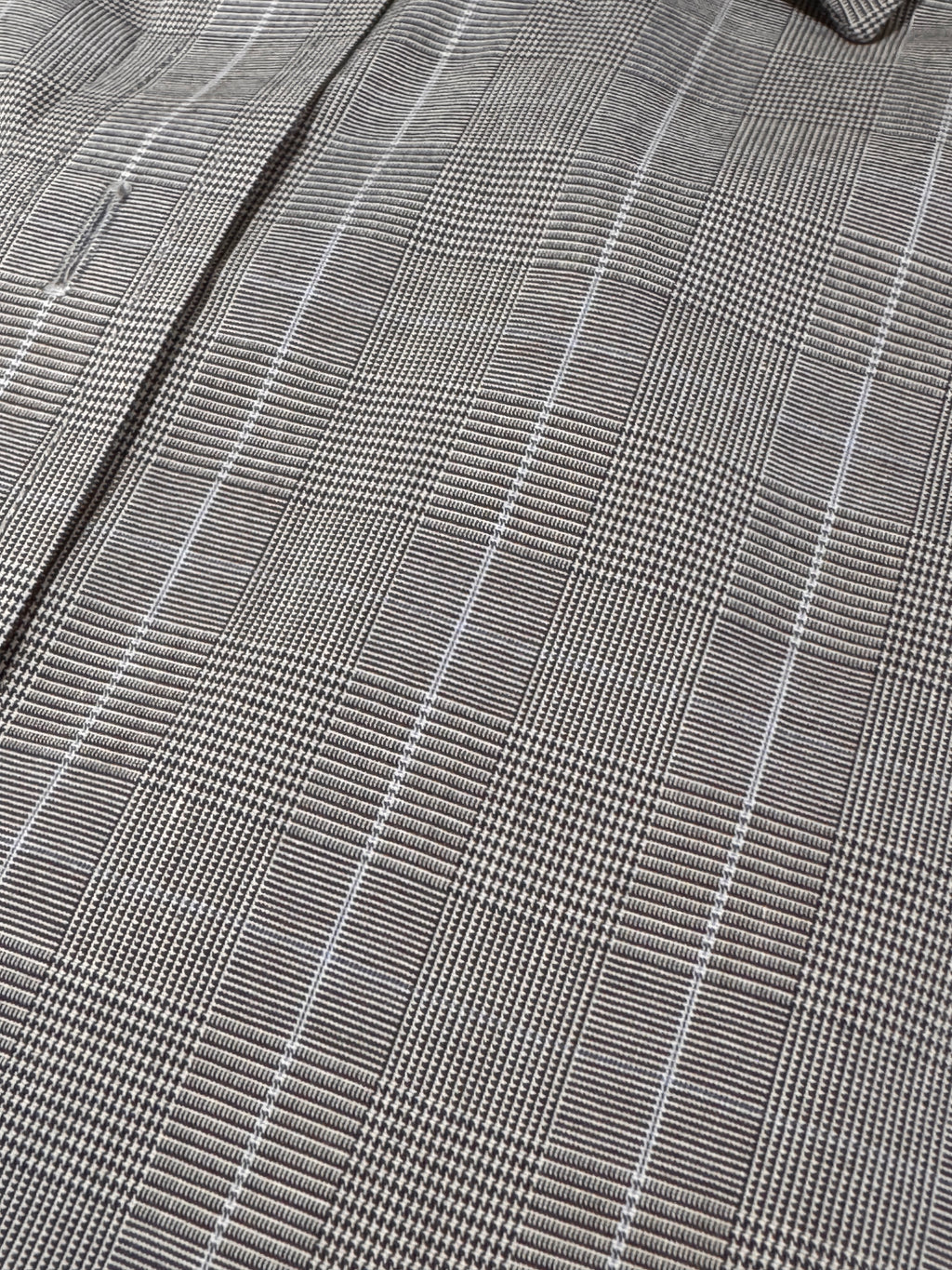 Close-up of a gray and white plaid fabric pattern with a fine woven texture.