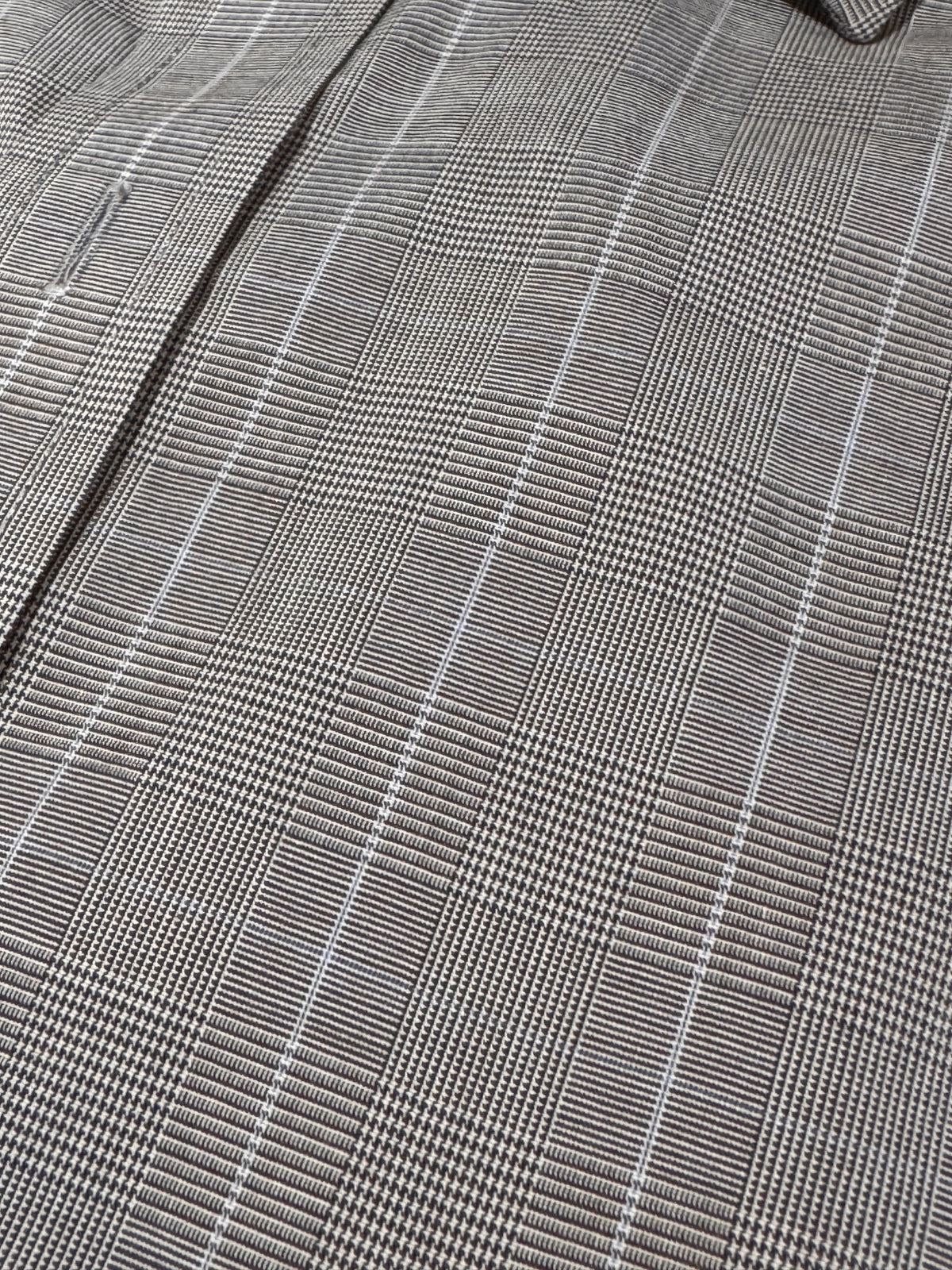 Close-up of a gray and white plaid fabric pattern with a fine woven texture.