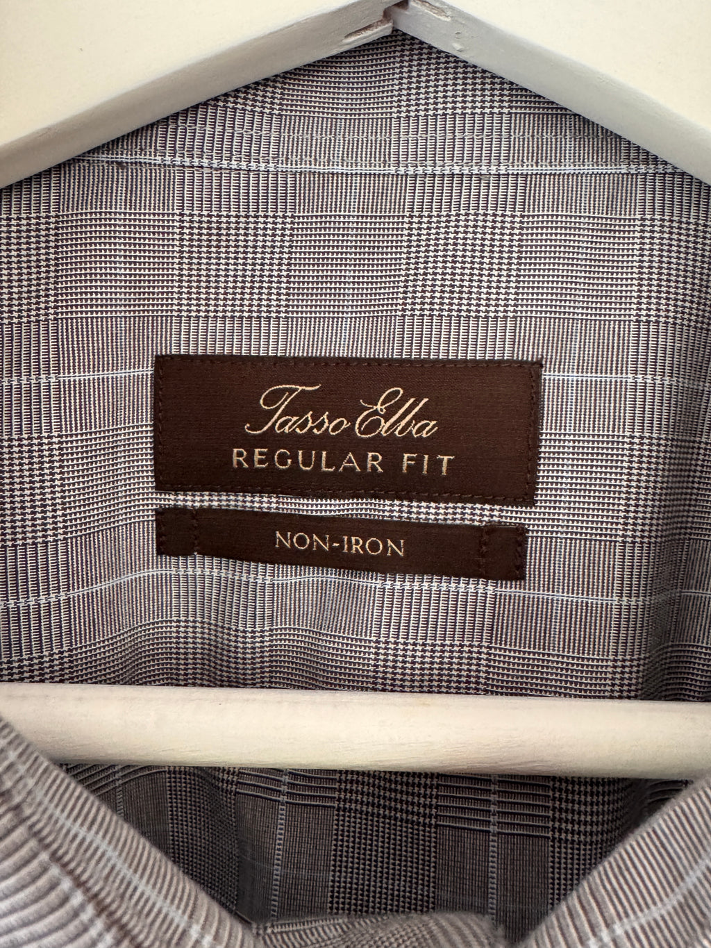 Close-up of the inside collar of a Tasso Elba Regular Fit non-iron shirt, showing the brown brand label and the gray and white plaid fabric.