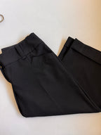 Folded pair of cropped black pants showing pockets and cuffs on a white background