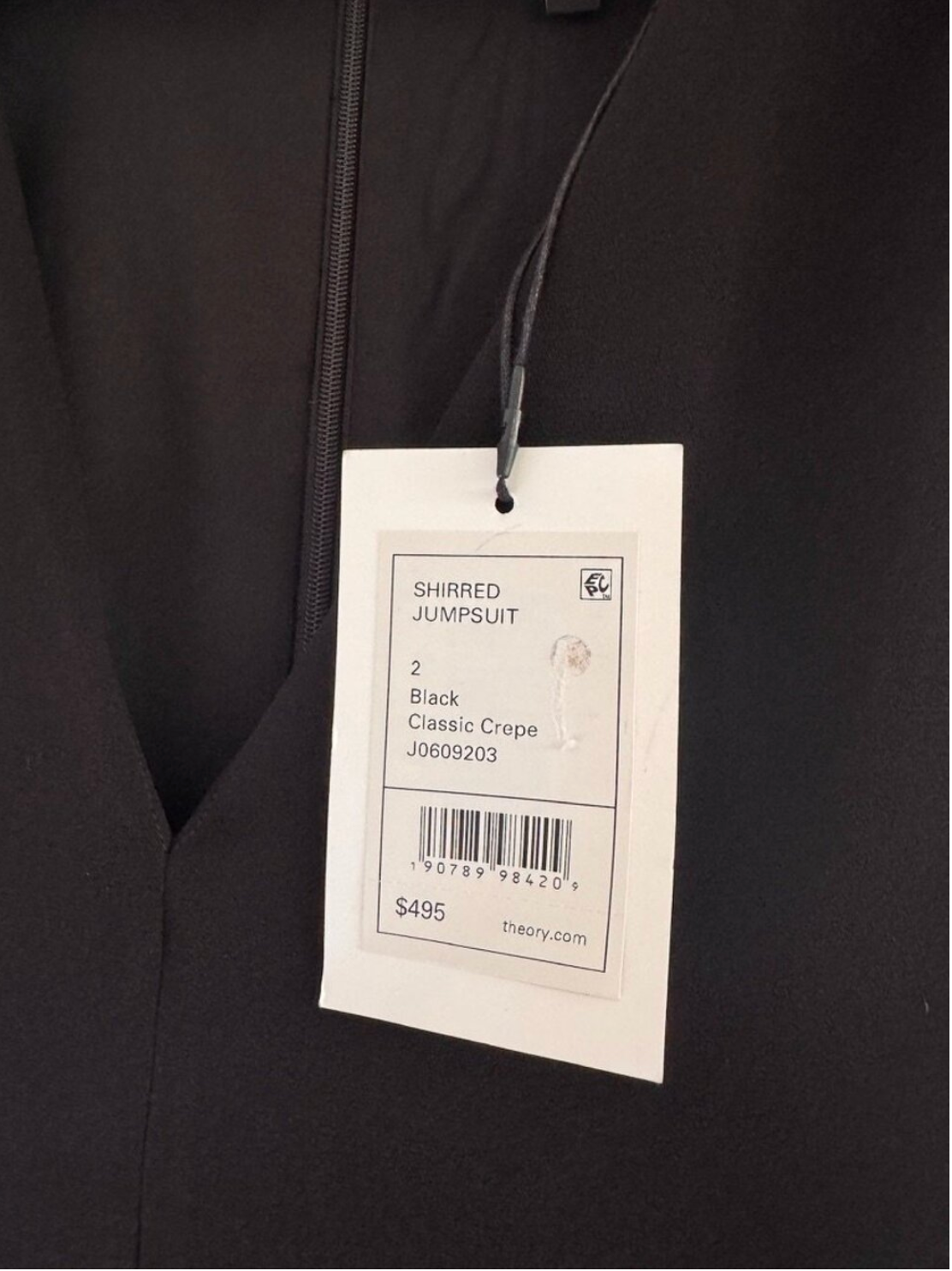 Black shirred jumpsuit with a tag displaying size and price details.