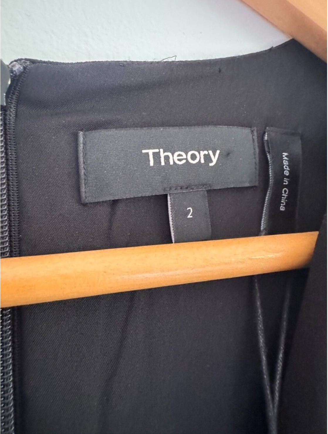 Black garment with 'Theory' label on a wooden hanger
