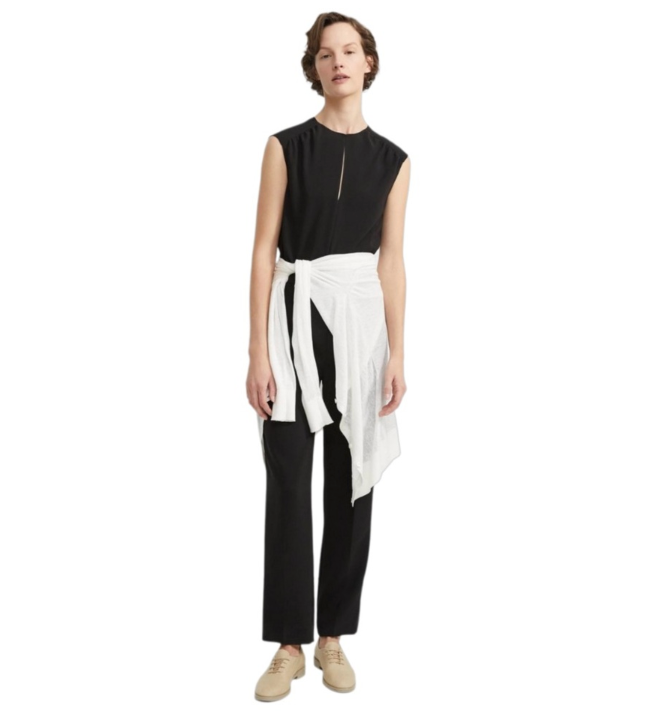 Person wearing a black sleeveless Theory  jumpsuit with a white sweater tied at the waist on a white background