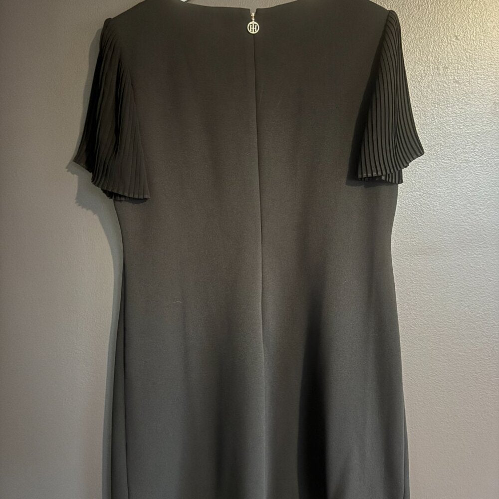 Black dress with pleated shoulders on a plain background