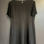 Black dress with pleated shoulders on a plain background