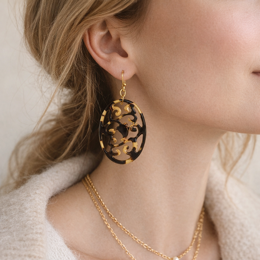 Close-up of a person wearing gold earrings and a necklace against a neutral background