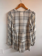 Plaid shirt on a hanger against a plain wall