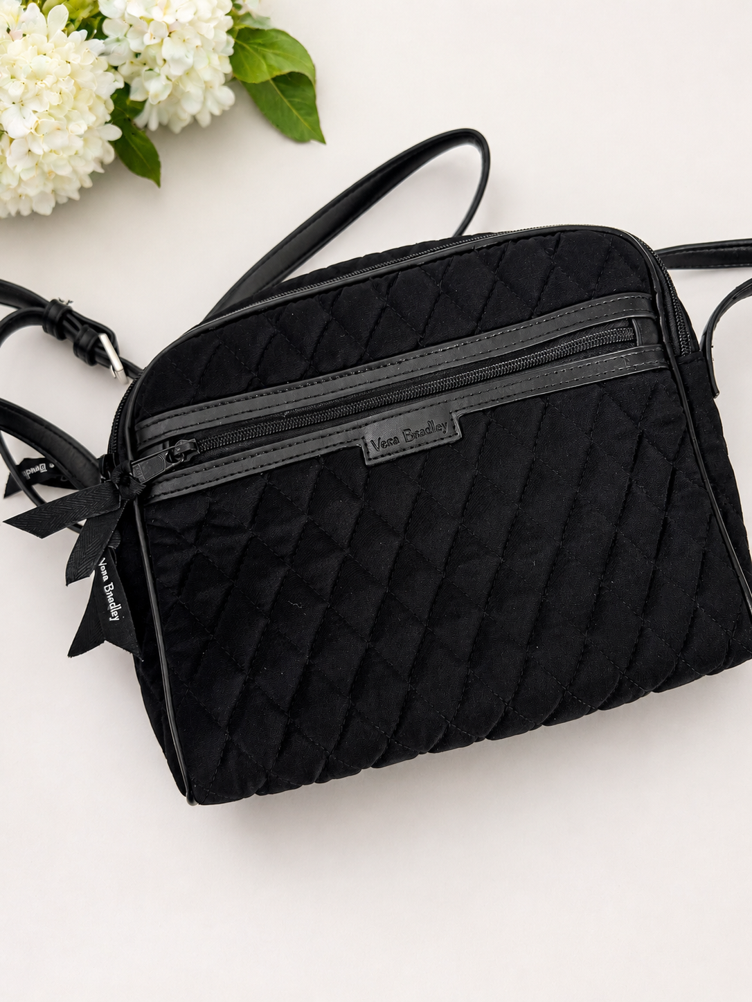 Black quilted handbag with floral decorations on a white background
