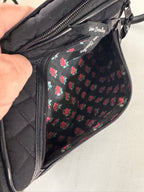 Black quilted bag with floral lining held by a hand against a neutral background