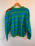 Green and blue striped sweater on a hanger against a white background