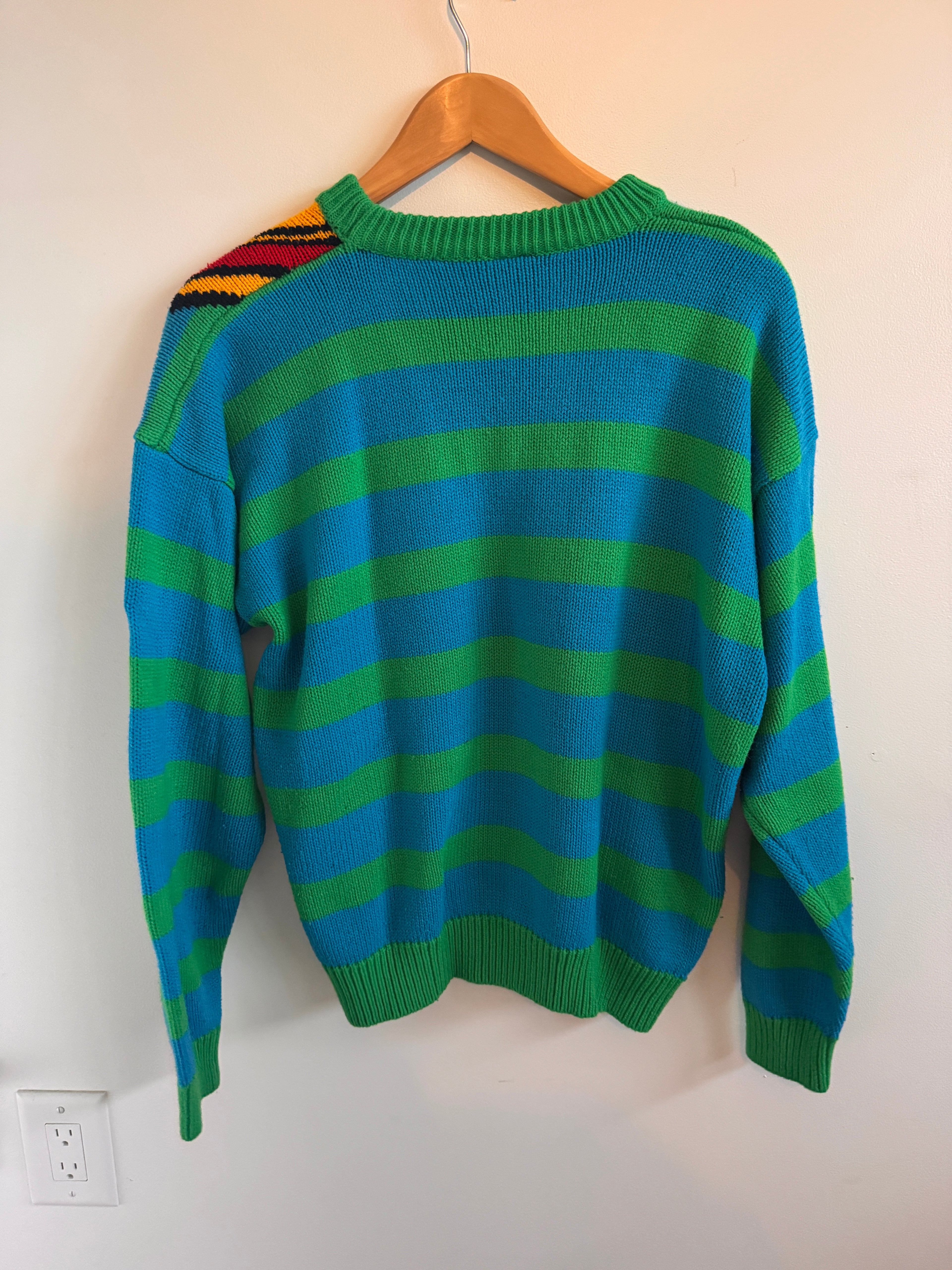 Green and blue striped sweater on a hanger against a white background
