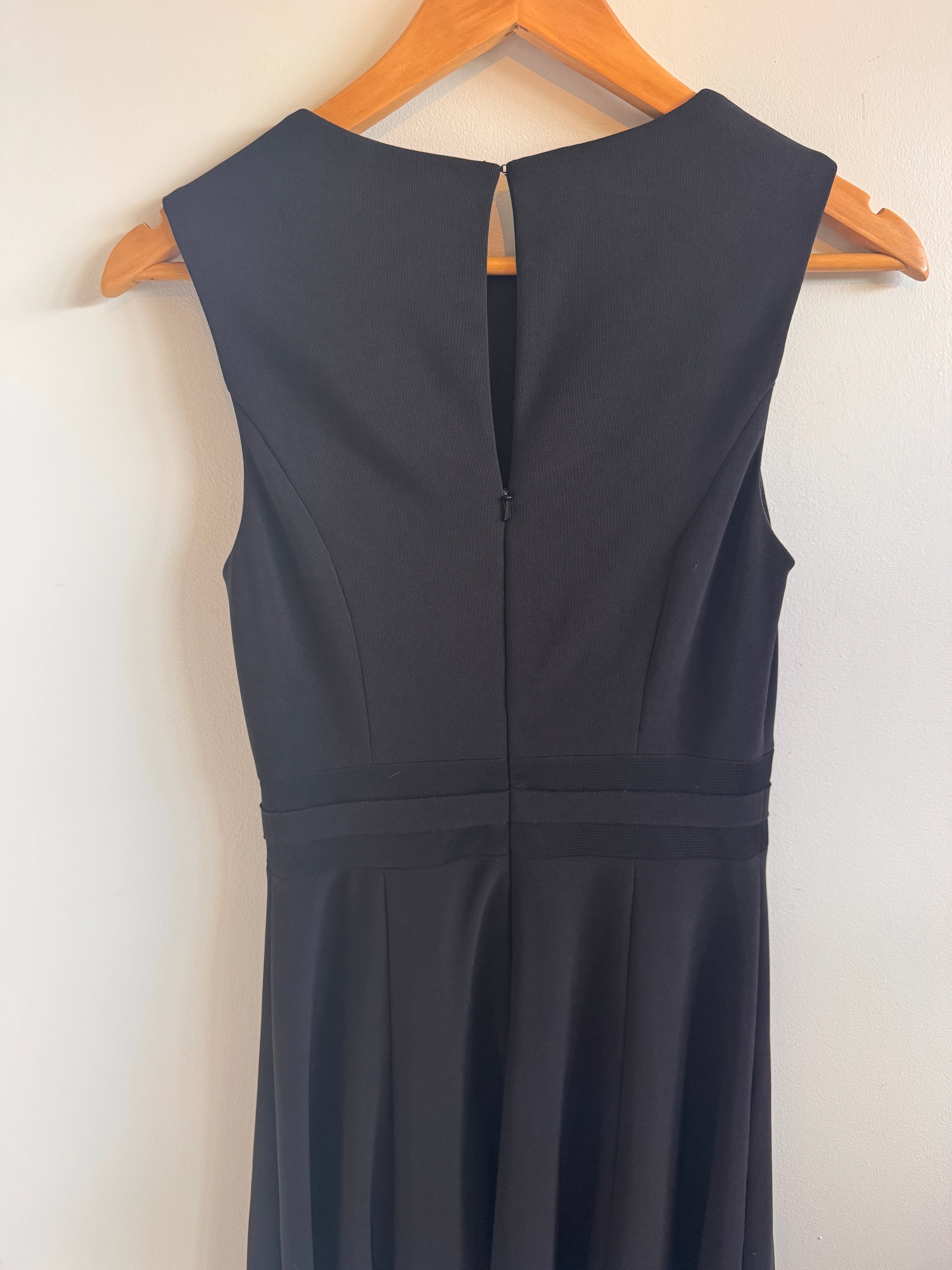 Black dress on a wooden hanger against a white background
