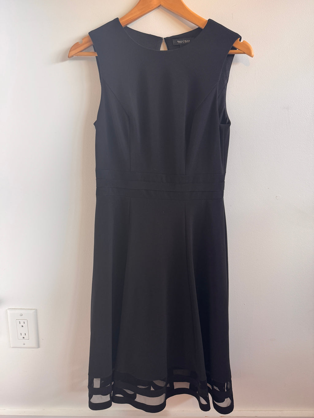 White House Black Market Dress hanging on a hanger against a white wall