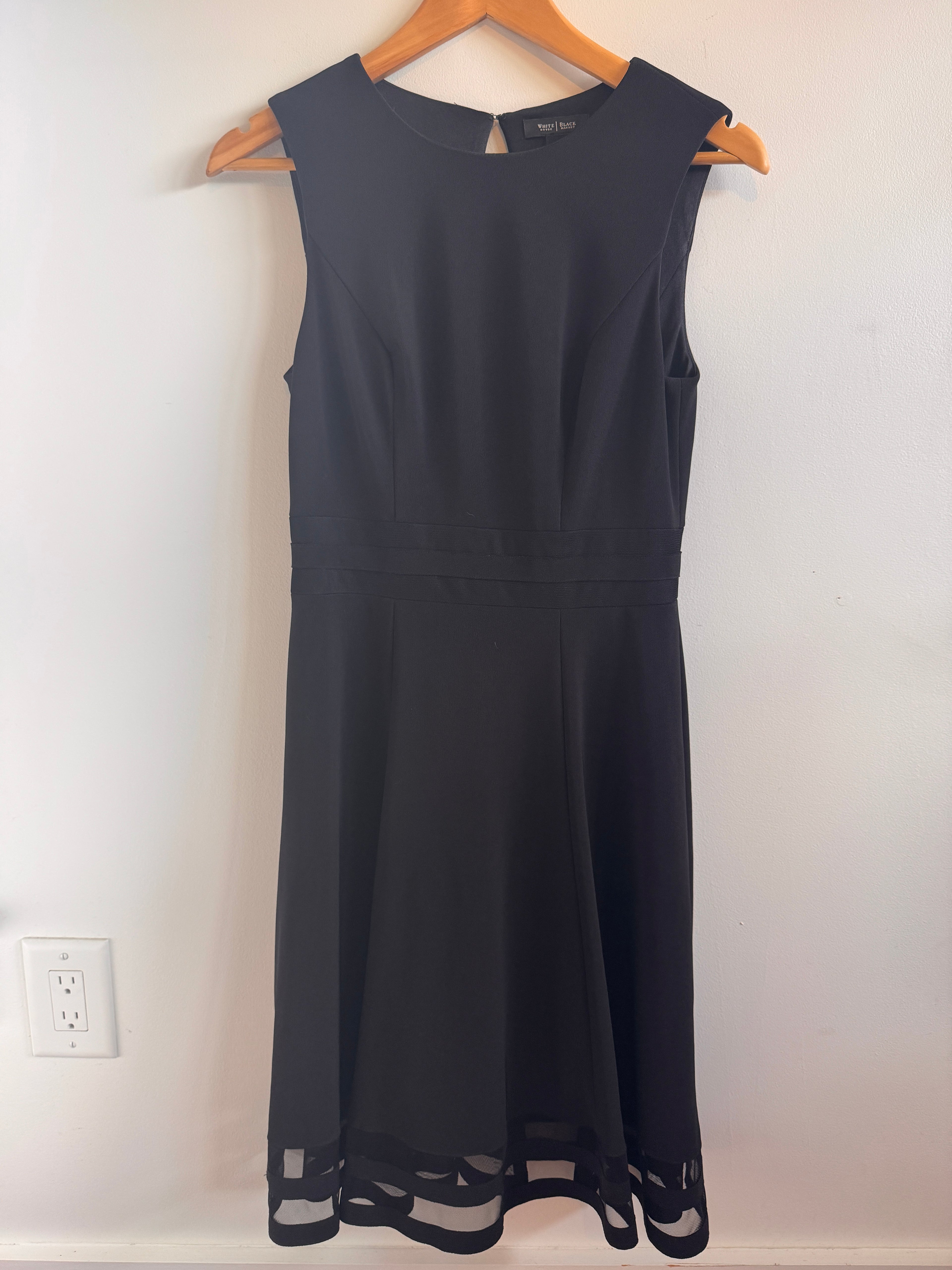 White House Black Market Dress hanging on a hanger against a white wall