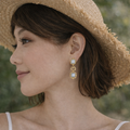 Woman wearing a straw hat and gold earrings with a blurred green background