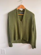 Green sweater on a hanger against a white background
