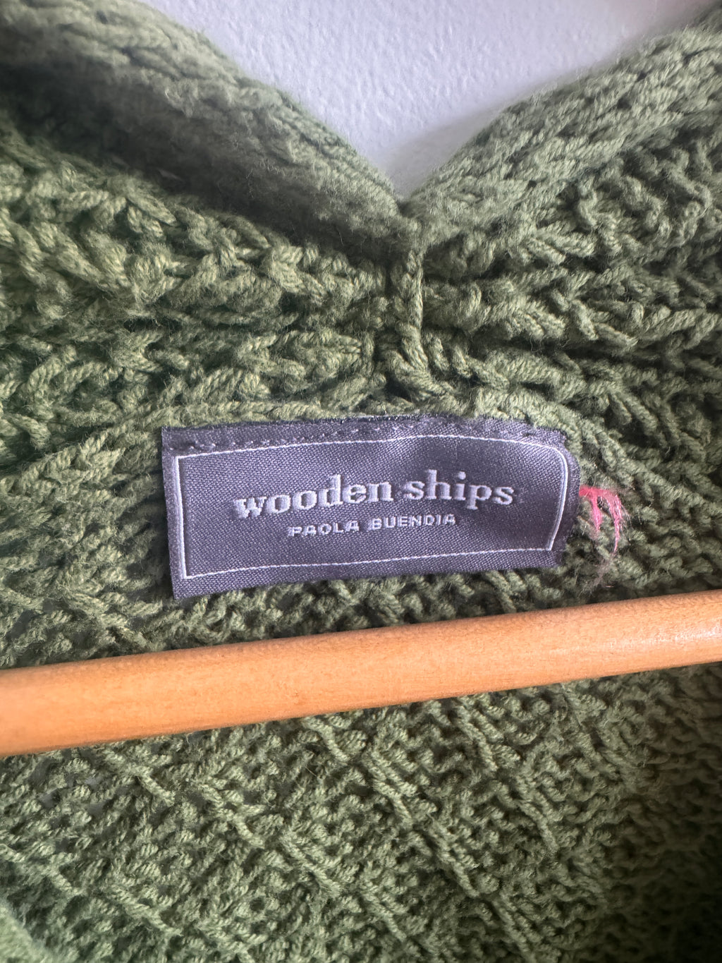 Green knitted fabric with a wooden knitting needle and 'woodenships' label.