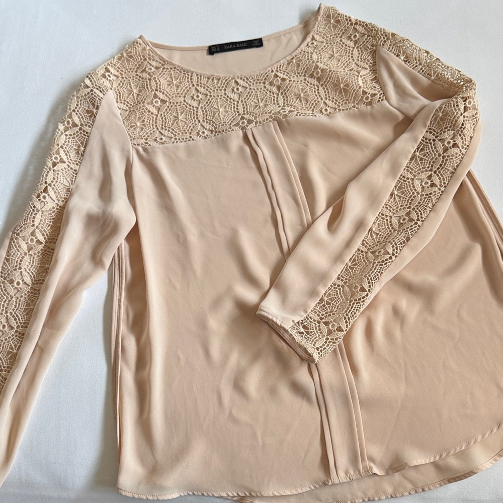 Beige long-sleeve top with lace detailing on a light gray background