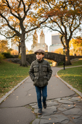 Young boy in olive puffer jacket with pageboy hat walking in Central Park