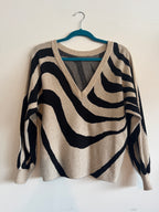 Zebra-striped sweater on a hanger against a white background