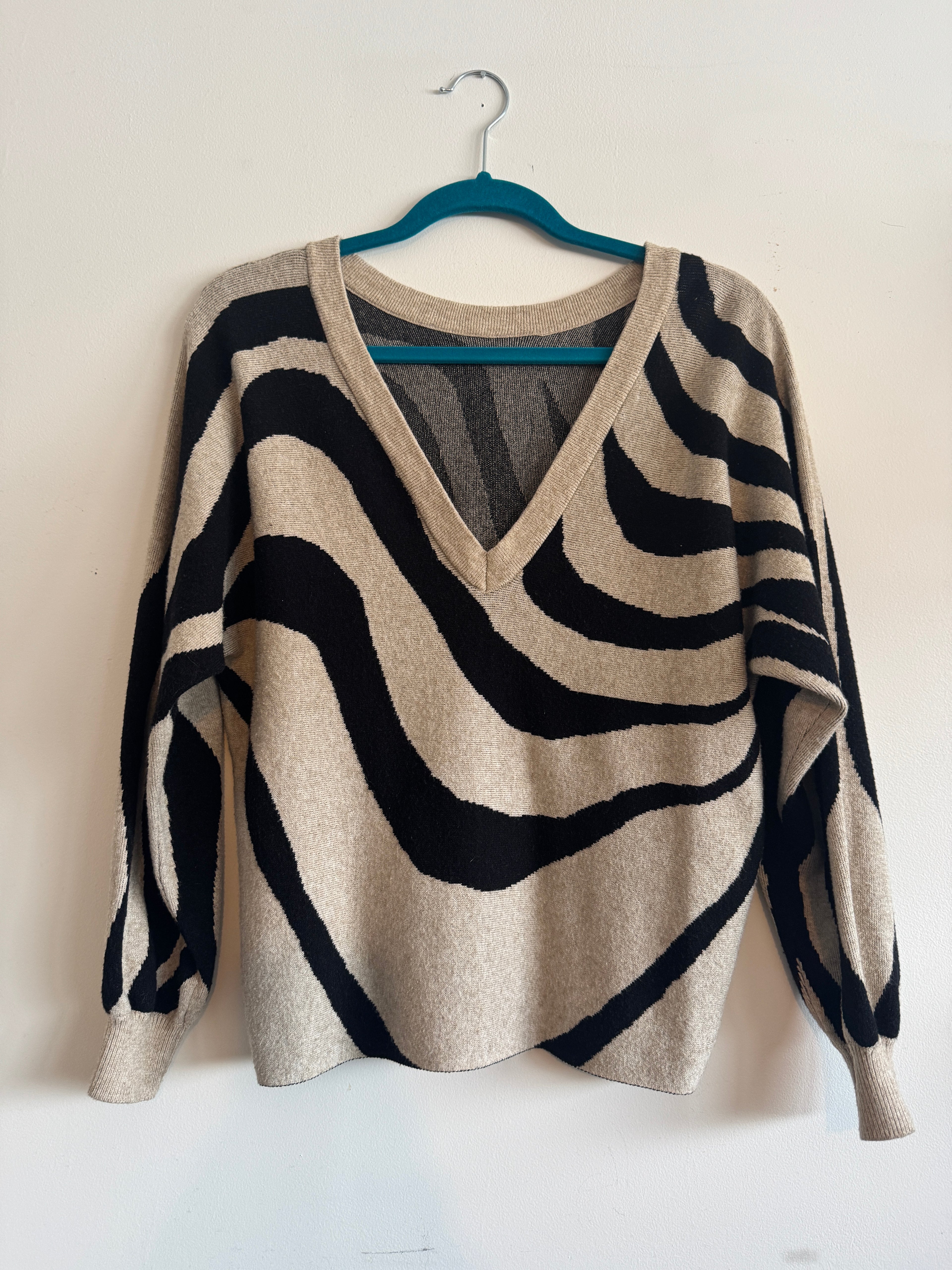 Zebra-striped sweater on a hanger against a white background