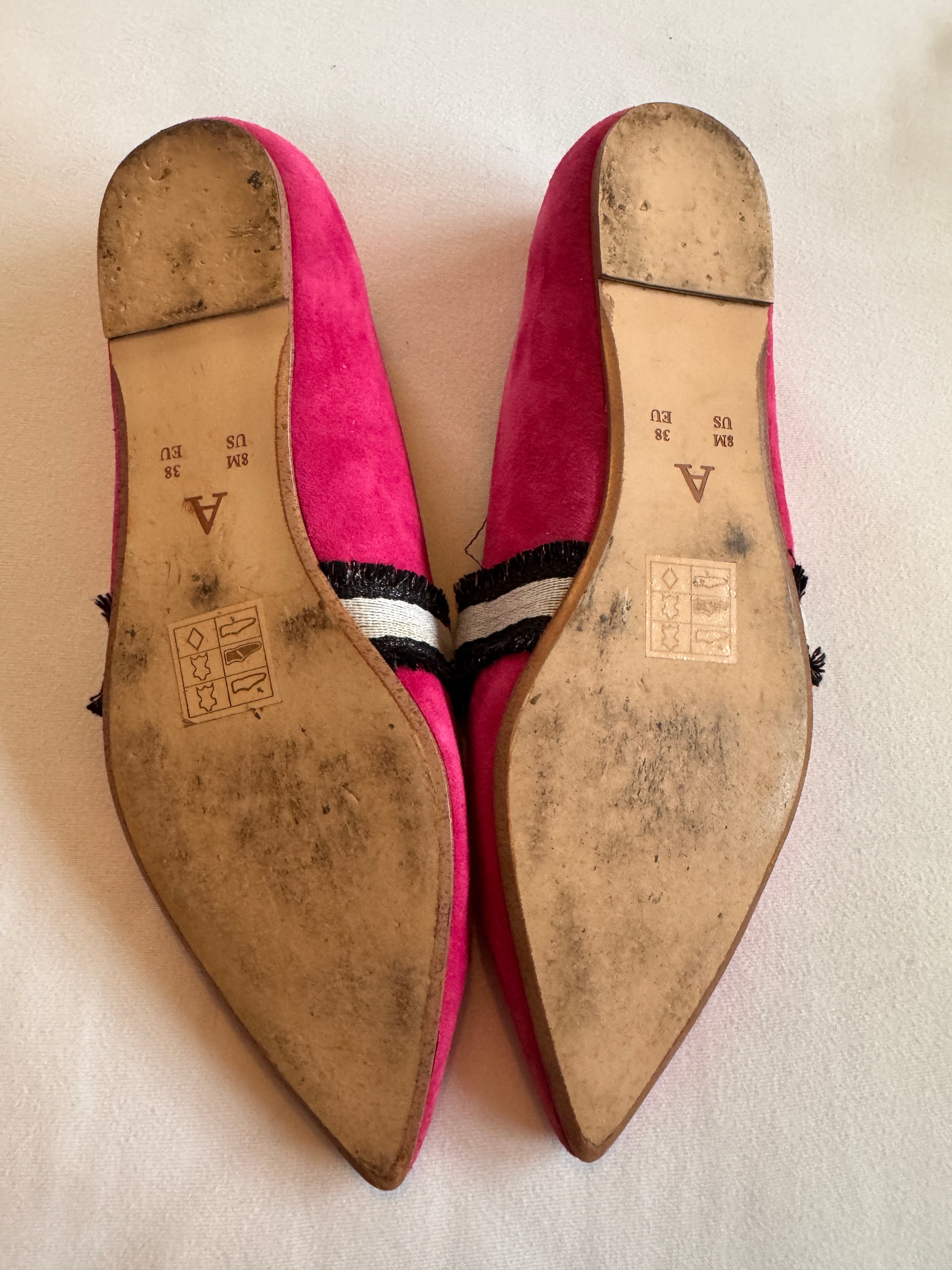 Pair of pink shoes with worn soles on a light background